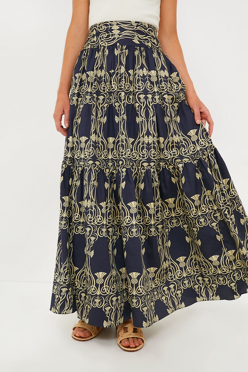 A person wears an Eugenia Fernandez navy blue and yellow patterned cotton maxi skirt with a white top and brown sandals—an effortless, sustainable fashion look.