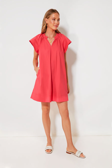 A woman wears a Pomander Place loose-fitting, short-sleeve pink mini dress with pockets, paired with sandals and layered necklaces.