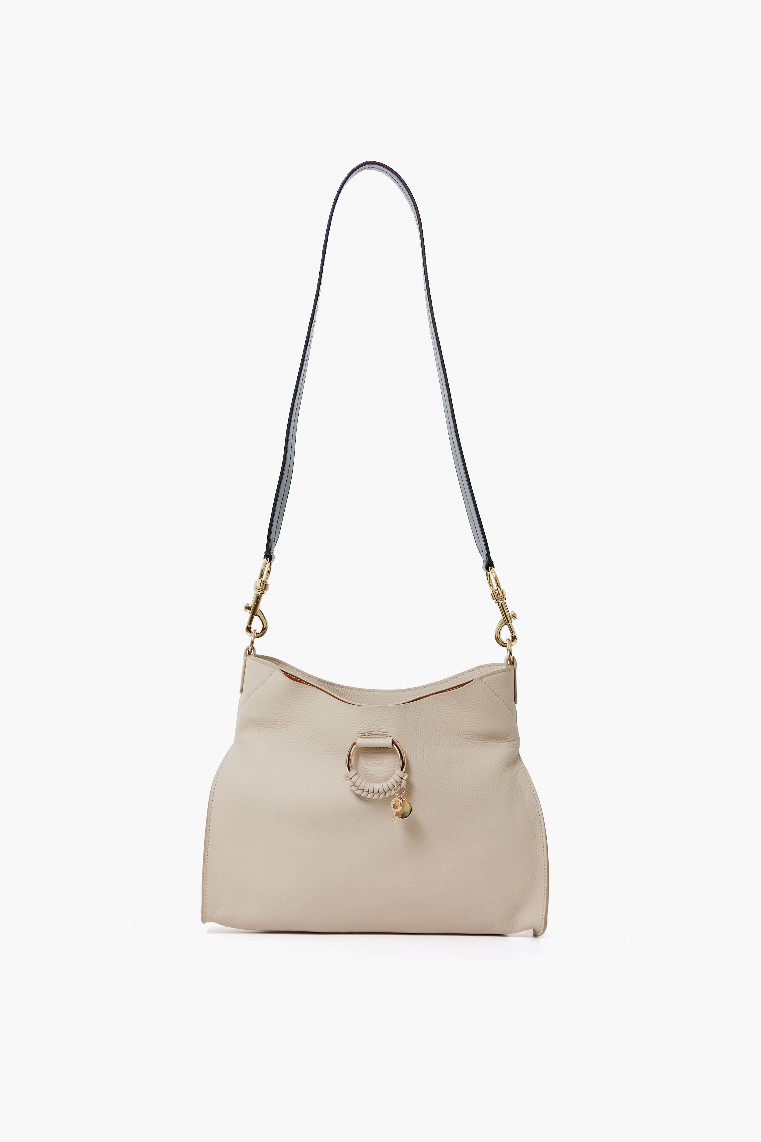 A beige See by Chloe Joan Bag with gold hardware, a circular ring detail, and a black adjustable strap for crossbody wear.